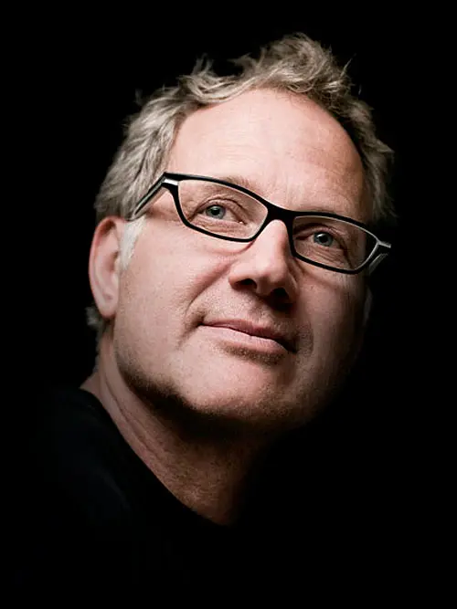 Portrait de Tinker Hatfield, le designer de Nike, sur un fond noir.